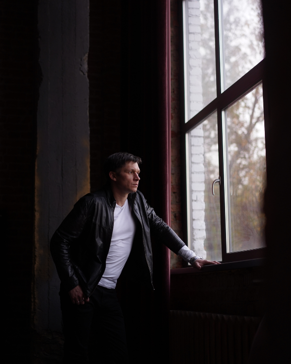 A person standing at a window looking out — reflective, at a crossroads, ready for a new direction