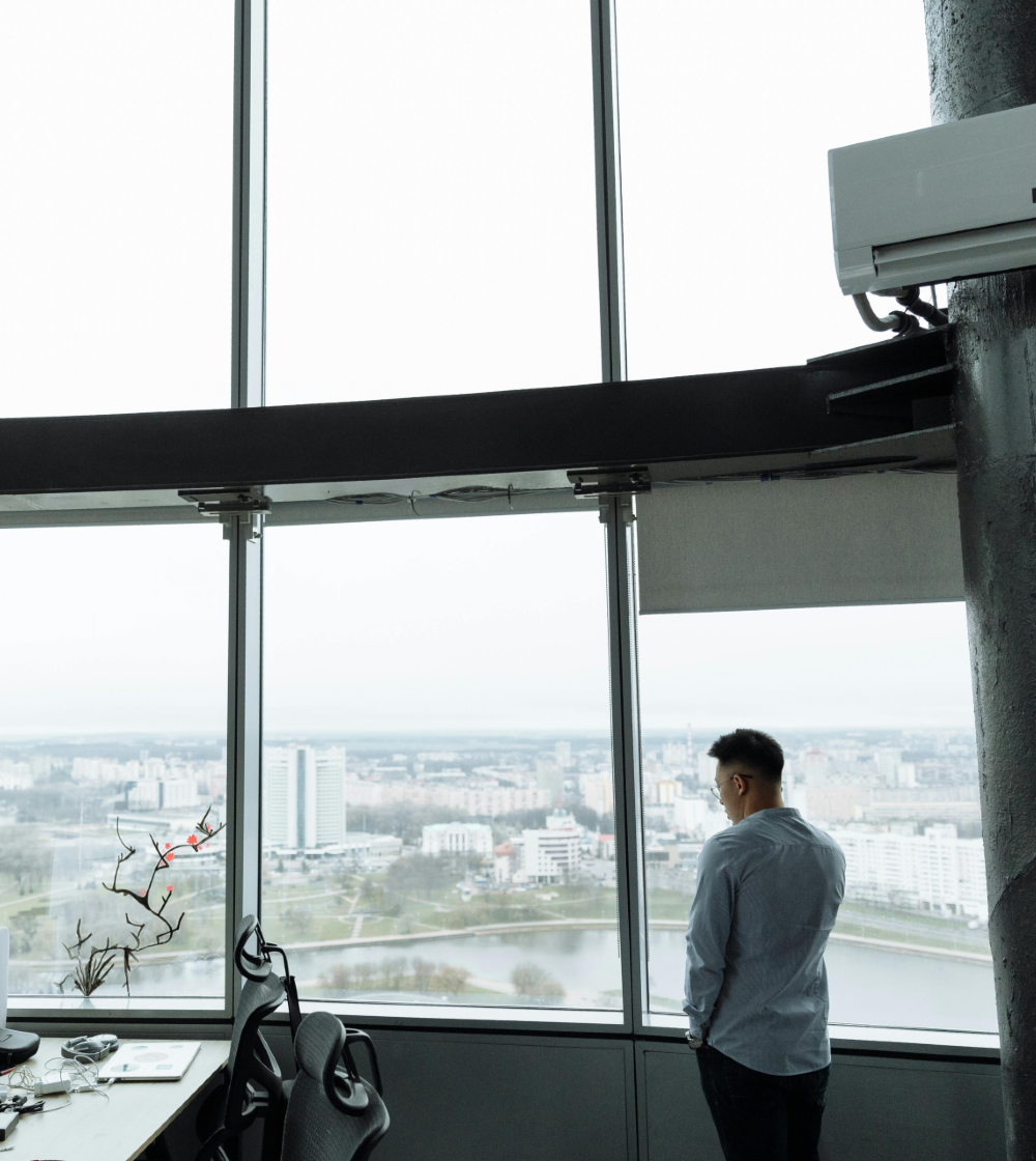 Senior executive contemplating next steps from a high-rise office — the moment high performance coaching addresses